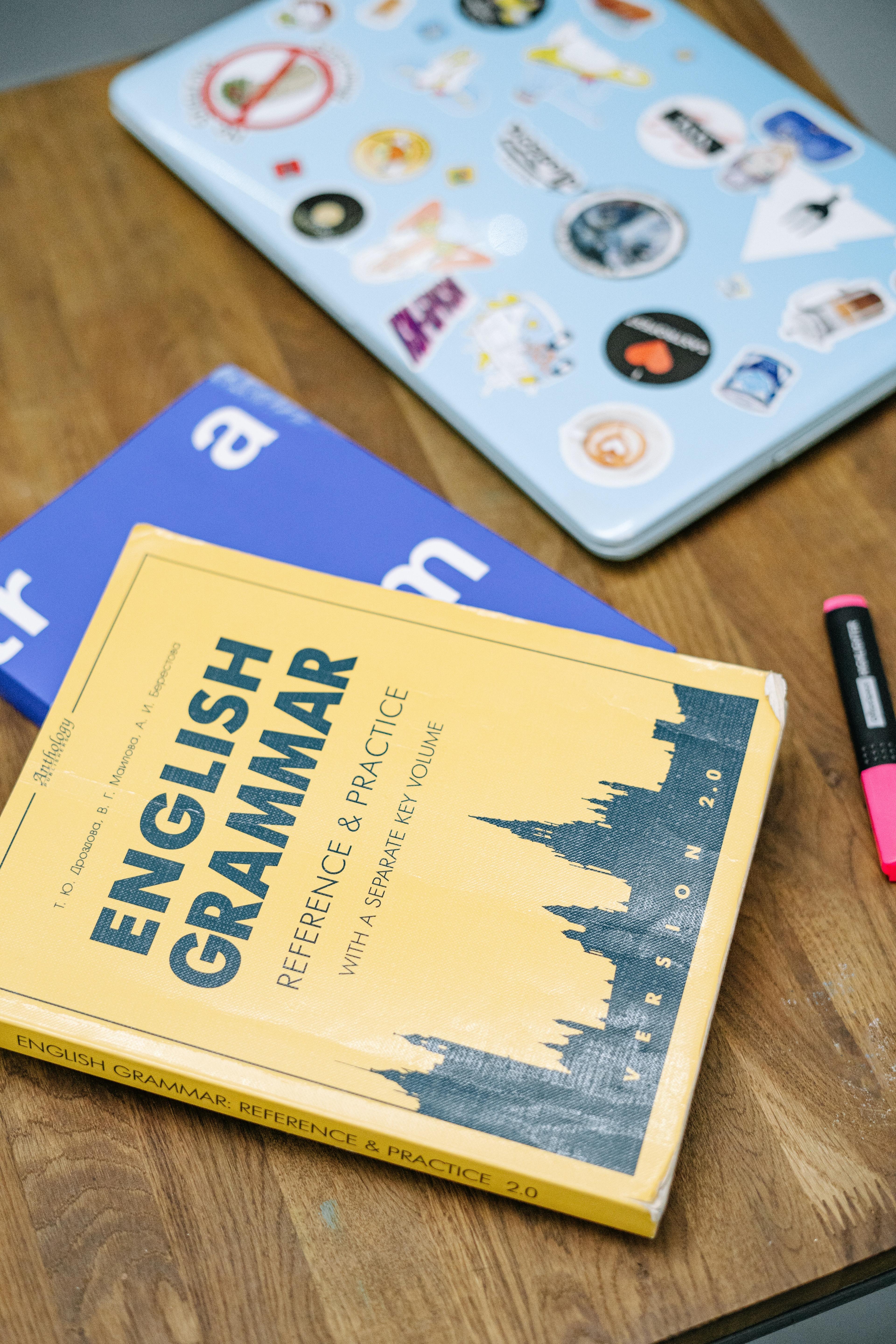 English workbooks beside a laptop on a desk